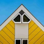 How to Choose the Best Siding for Your Home: Expert Tips and FAQs 6 A striking roof on a cubic house. It is bright yellow with angled siding and geometric windows.