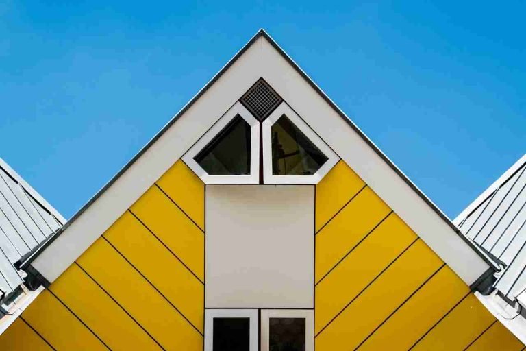 A striking roof on a cubic house. It is bright yellow with angled siding and geometric windows.